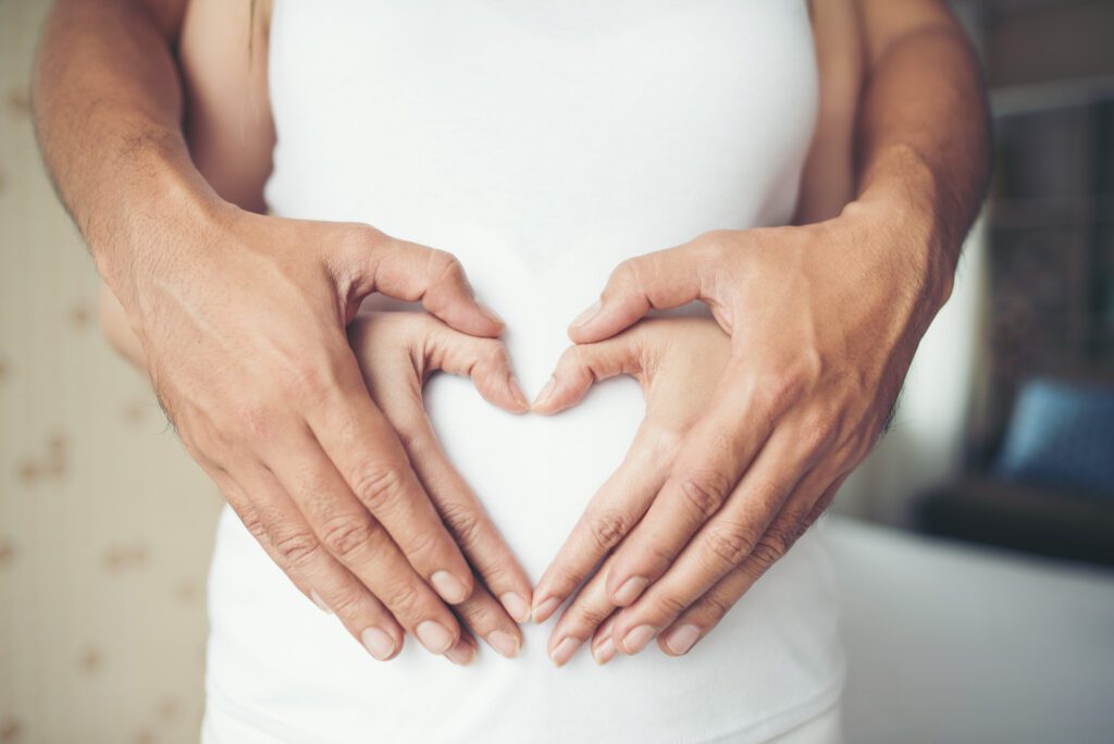 pregnant woman her husband hand showing heart shape edited